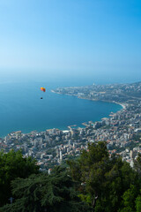 A breathtaking aerial view of Jounieh’s seaside with resorts, boats, and paragliders over the...