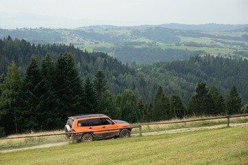Jadące terenowe auto szlakiem górskim, w oddali widać góry © Stefan