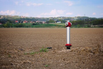 Hydrant do wody wystający z ziemi w tle widać na zielonym horyzoncie dachy domów © Stefan
