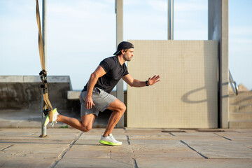Man in black and grey sportswear performing resistance band running drills outdoors