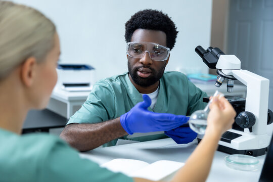 Diverse team of professional scientists chemists in lab using equipment