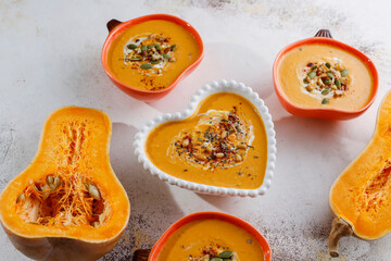 Traditional autumn butternut squash soup with seeds in a heart-shaped bowl.