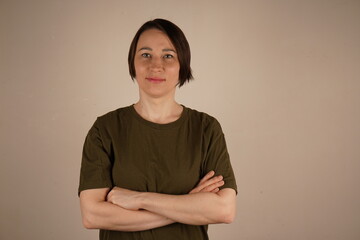 A brunette girl with short hair and brown eyes. She crossed her arms in front of her. Close-up photo.