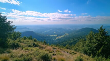 Panoramic View of Rolling Hills and Forested Valleys under a Blue Sky with Clouds