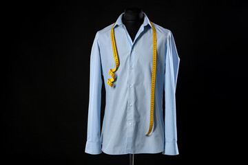 Male mannequin with shirt and measuring tape on black background