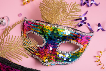 Festive face mask for carnival celebration on colored background top view