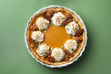 Tasty homemade pumpkin pie in baking dish on green table, top view