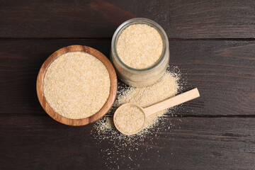 Oat bran in glass jar, bowl and spoon on wooden table, above view