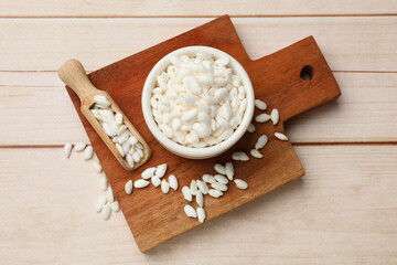 Bowl and scoop with puffed rice on white wooden table, top view