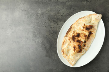 One delicious calzone on grey textured table, top view. Space for text