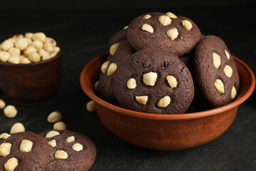Tasty chocolate cookies with hazelnuts on black table, closeup