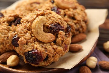 Delicious oatmeal cookies with raisins and nuts on wooden table, closeup