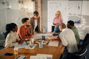 Marketing team analyzing diagrams and discussing new strategy during a meeting