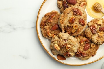 Tasty cookies with nuts and honey on white marble table, top view. Space for text