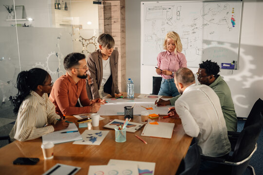 Marketing team analyzing diagrams and discussing new strategy during a meeting - Powered by Adobe