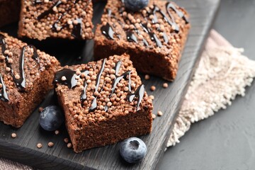 Delicious chocolate puffed rice bars and blueberries on gray table, closeup