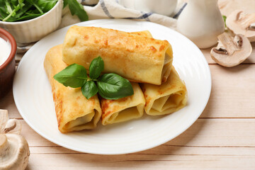 Delicious rolled crepes with basil and mushrooms on wooden table, closeup