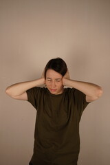 The girl turned straight and covered her ears. She shows her uncontrollable headache. Close up.