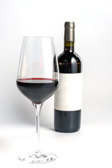 Glass of Red Wine with Bottle in Background on White.