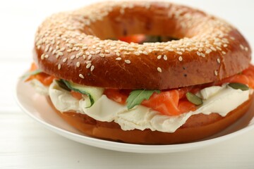 Delicious bagel with salmon and cream cheese on white wooden table, closeup