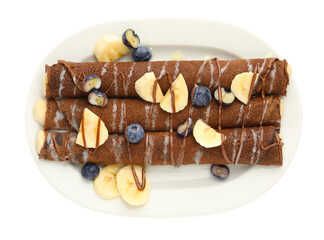 Delicious chocolate crepes with banana and blueberries isolated on white, top view