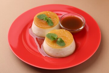 Tasty puddings with caramel sauce served on light brown background, closeup