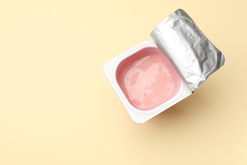 Delicious yogurt in plastic cup on beige background, top view. Space for text