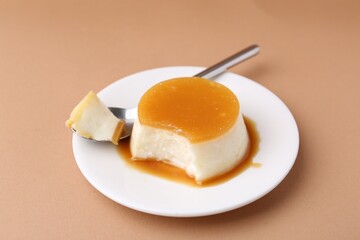 Fototapeta premium Tasty pudding with caramel sauce served on light brown background, closeup