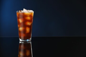 Refreshing iced coffee in glass on mirror surface. Space for text