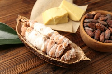 Cocoa pod with beans and butter on wooden table, closeup