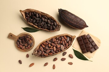 Cocoa pods with beans and chocolate on beige background, flat lay