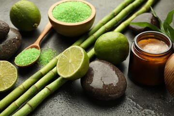 Spa composition with wet limes, sea salt, pebble stones and bamboo stems on grey table, closeup
