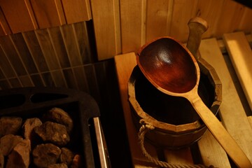 Bucket and ladle on wooden bench in sauna, closeup