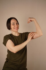 Demonstrating one of her biceps, the girl is satisfied with the results of her training. Woman...