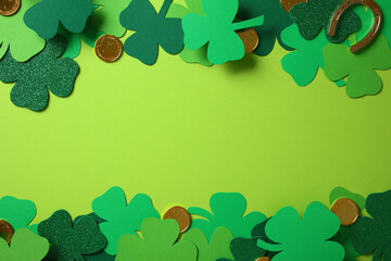 Happy St Patrick's Day frame made of four leaf clover, gold coins, and shamrocks on green background
