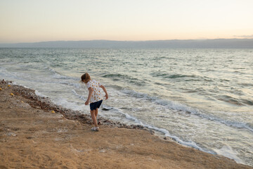 A girl stands still on the salty shore, embracing nature’s beauty. Wellness themes, travel...