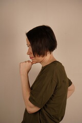 A close-up shot of a brunette with gray eyes looking dreamily to the side and holding her chin. She...