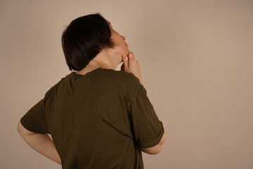 A brunette standing with her back is photographed. She is slightly turned and looks to the side....