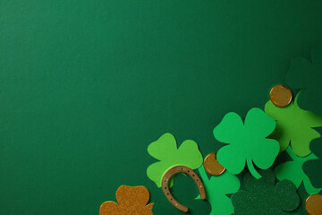 St. Patrick's Day concept with green shamrocks, gold coins, and a horseshoe on a dark green...