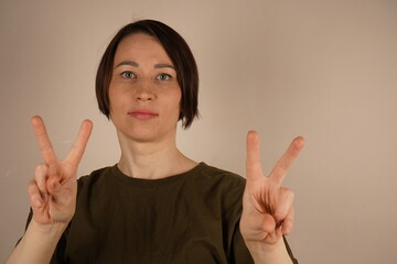 The petite woman stands confidently with short brunette hair neatly styled above her shoulders and...