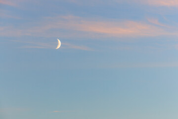 Crescent moon in tranquil evening sky with soft pink clouds