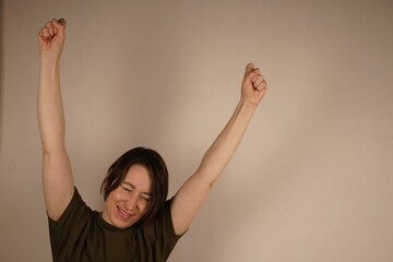 Top view of happy young fashionable woman raising hands over gray background in studio.