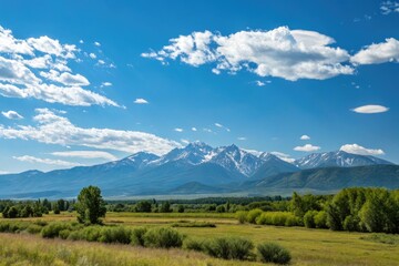 Fototapeta premium A sunny blue sky with few wispy clouds and a majestic mountain range in the distance, mountains, open