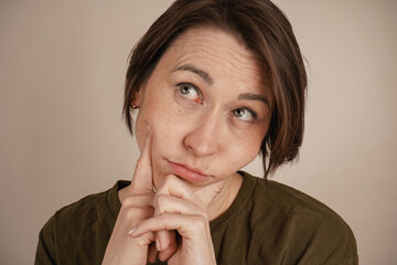 Close-up photo. Happy dark-haired girl grimacing at the camera while standing on a white...
