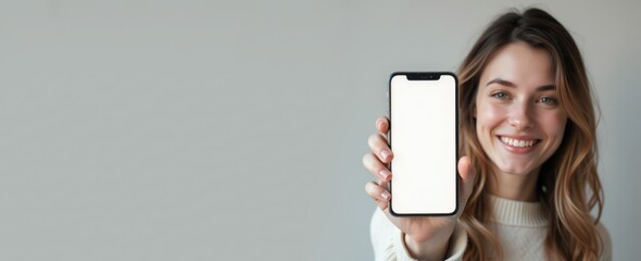 Cheerful woman displaying a blank smartphone screen mockup for banner or app design.