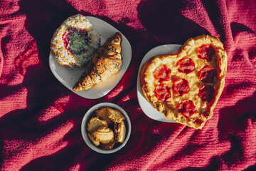 Food for a picnic, heart-shaped pizza, croissant and cookies on a picnic blanket