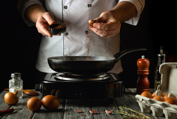 A skilled cook prepares a delicious meal by adding spices to a sizzling pan. Fresh eggs and...
