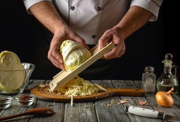 Under the warm glow of evening light, a skilled chef delicately shreds fresh cabbage using a...