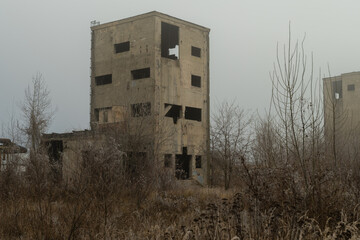 Creepy concrete building in an abandoned industrial area covered in winter fog