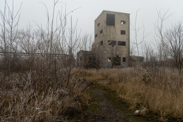 Creepy concrete building in an abandoned industrial area covered in winter fog